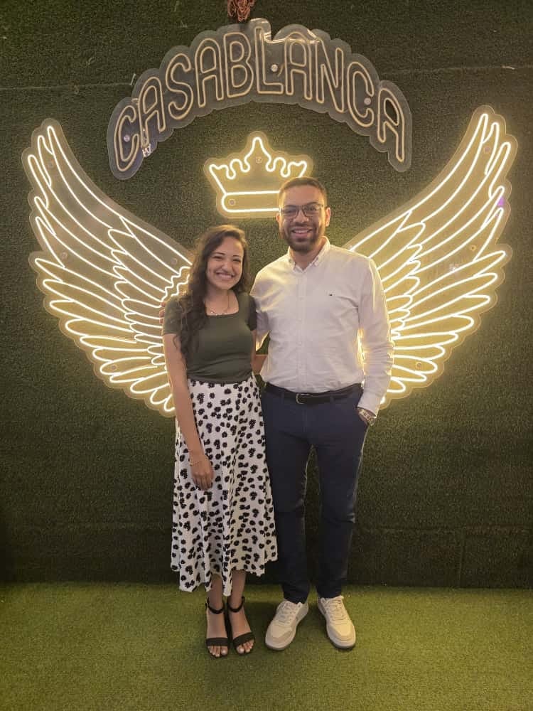 Nada and John in front of glowing neon wings