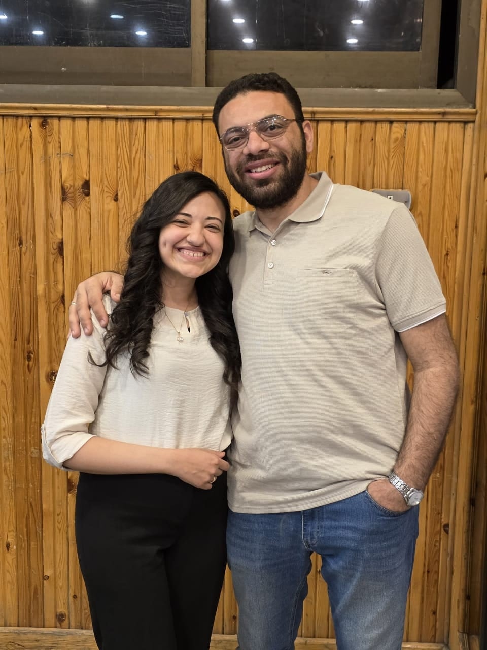 Nada and John in front of a wooden wall